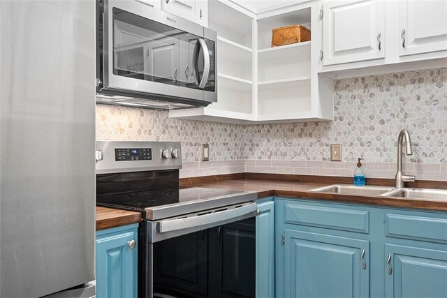 588 NW 105th Rd, Centerview, MO 64019 - kitchen featuring stainless steel appliances, blue cabinets, a sink, decorative backsplash, and white cabinetry