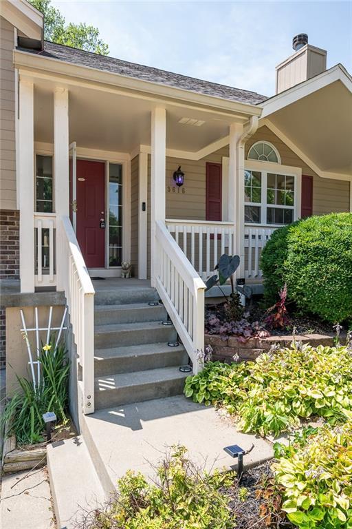 3616 Anchor Ct, Blue Springs, MO 64015 - property entrance with a chimney, a porch, a shingled roof, and brick siding