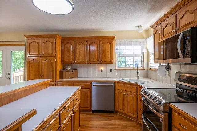 3616 Anchor Ct, Blue Springs, MO 64015 - kitchen featuring appliances with stainless steel finishes, healthy amount of natural light, brown cabinetry, decorative backsplash, and a textured ceiling
