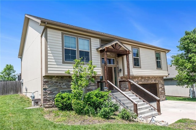 split foyer home with stone siding, an attached garage, and driveway