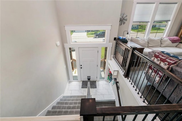 foyer with marble finish floors, baseboards, and stairs