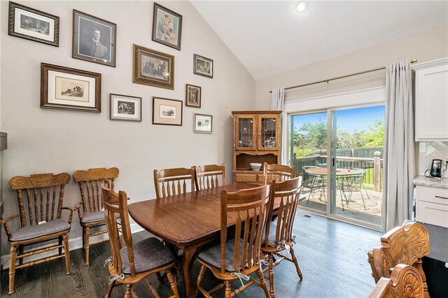 dining area featuring wood finished floors and high vaulted ceiling