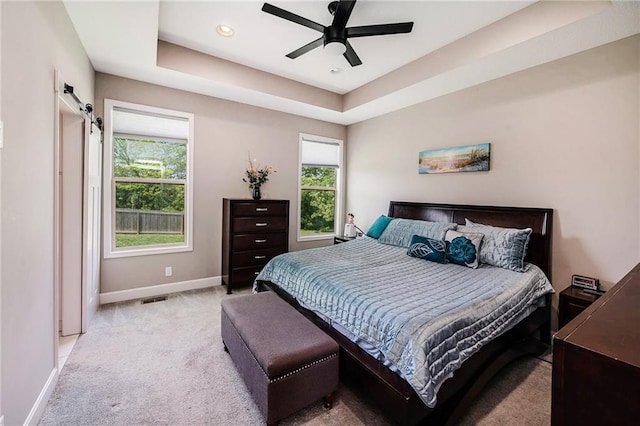 bedroom with baseboards, light carpet, a tray ceiling, ceiling fan, and recessed lighting