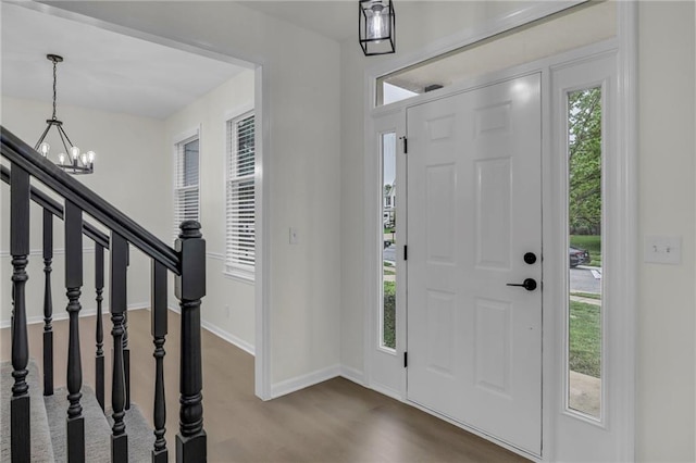 entrance foyer with an inviting chandelier, baseboards, and dark wood-style flooring