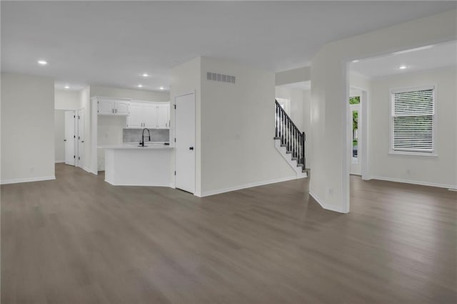 unfurnished living room with visible vents, dark wood-style flooring, stairs, baseboards, and recessed lighting
