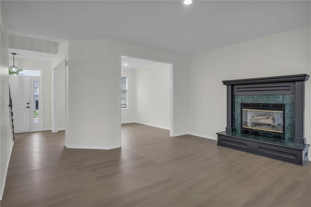 unfurnished living room featuring a tiled fireplace, baseboards, recessed lighting, and wood finished floors