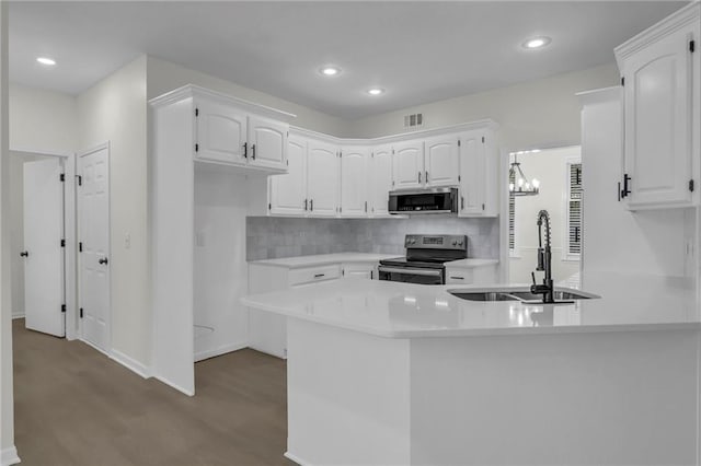kitchen with a sink, stainless steel appliances, a peninsula, dark wood-type flooring, and visible vents