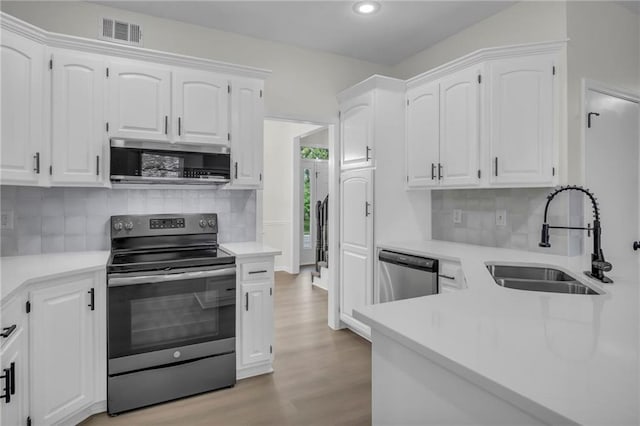 kitchen with a sink, appliances with stainless steel finishes, light wood-style floors, and visible vents
