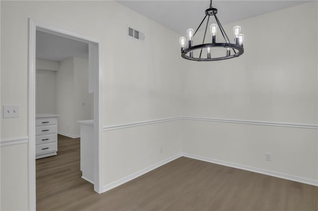 unfurnished dining area with visible vents, baseboards, wood finished floors, and a notable chandelier