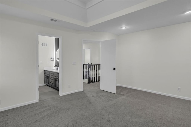 spare room with baseboards, visible vents, a sink, and carpet