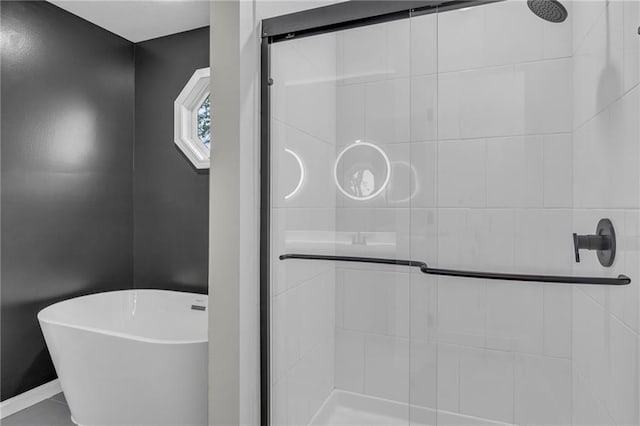 full bath with baseboards, a soaking tub, and a shower stall