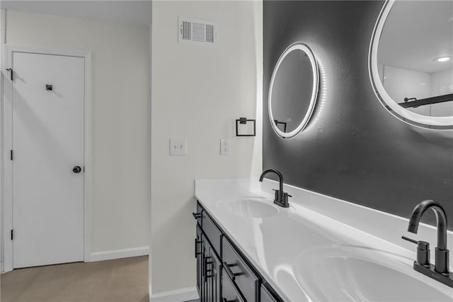 full bath with visible vents, a sink, baseboards, and double vanity