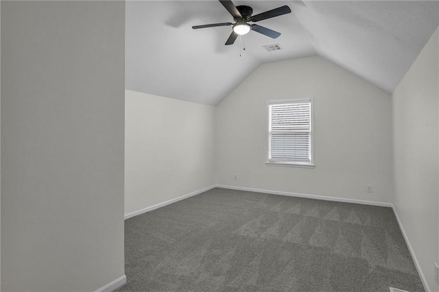 additional living space featuring baseboards, lofted ceiling, dark colored carpet, and visible vents
