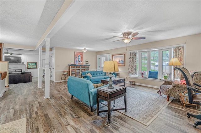8739 Lafayette Ave, Kansas City, KS 66109 - living room with a ceiling fan, a textured ceiling, wood finished floors, ornate columns, and baseboards