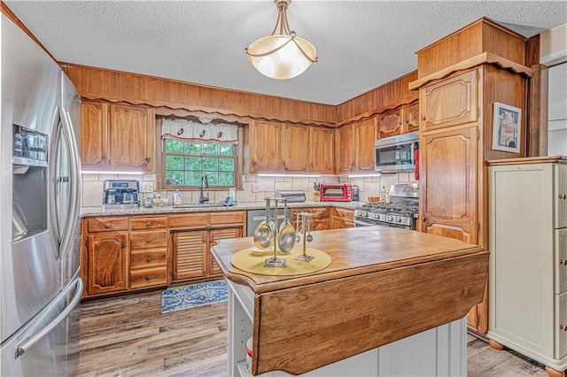 8739 Lafayette Ave, Kansas City, KS 66109 - kitchen with appliances with stainless steel finishes, a sink, a textured ceiling, a center island, and light wood-style floors