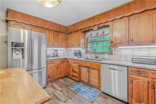 8739 Lafayette Ave, Kansas City, KS 66109 - kitchen featuring appliances with stainless steel finishes, a sink, tasteful backsplash, light wood-style flooring, and a textured ceiling