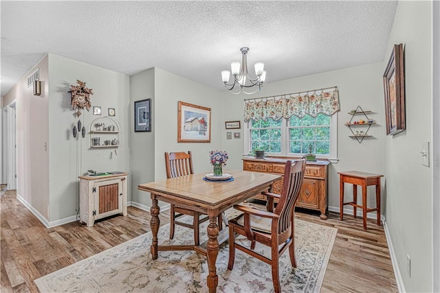 8739 Lafayette Ave, Kansas City, KS 66109 - dining room with light wood-style flooring, a chandelier, a textured ceiling, and baseboards