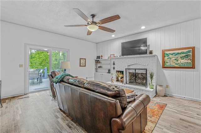 8739 Lafayette Ave, Kansas City, KS 66109 - living room featuring light wood finished floors, ceiling fan, a fireplace, a textured ceiling, and recessed lighting