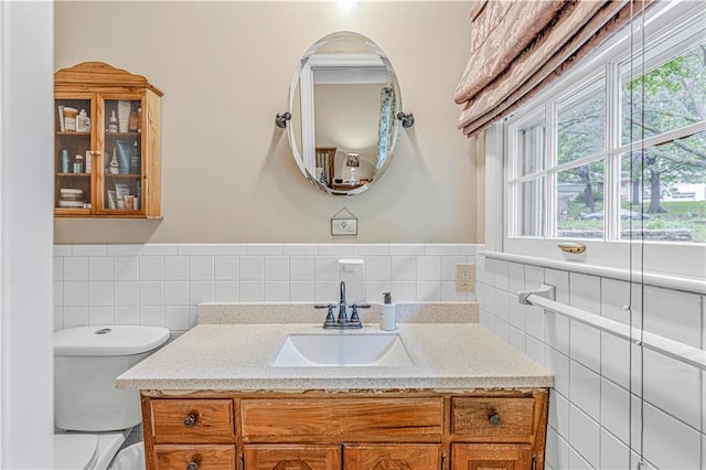 8739 Lafayette Ave, Kansas City, KS 66109 - bathroom with tile walls, vanity, toilet, plenty of natural light, and a wainscoted wall