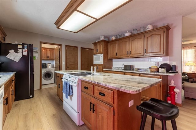 403 S 2nd St, Drexel, MO 64742 - kitchen with light wood-type flooring, brown cabinets, washer / clothes dryer, and white appliances