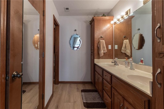 403 S 2nd St, Drexel, MO 64742 - full bath featuring baseboards, visible vents, a sink, double vanity, and wood finished floors