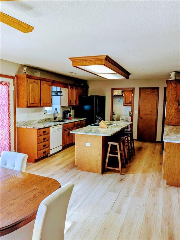 403 S 2nd St, Drexel, MO 64742 - kitchen with freestanding refrigerator, a sink, white dishwasher, a center island, and brown cabinets