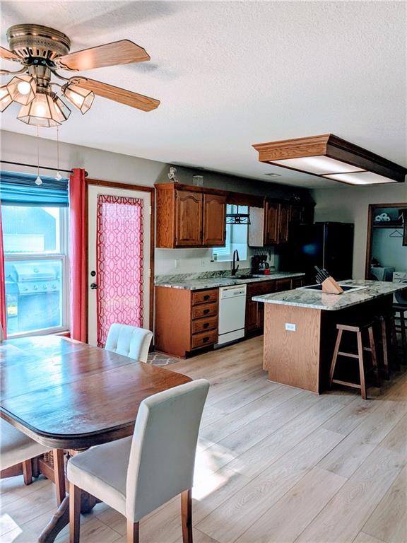 403 S 2nd St, Drexel, MO 64742 - kitchen with white dishwasher, a sink, plenty of natural light, freestanding refrigerator, and a textured ceiling