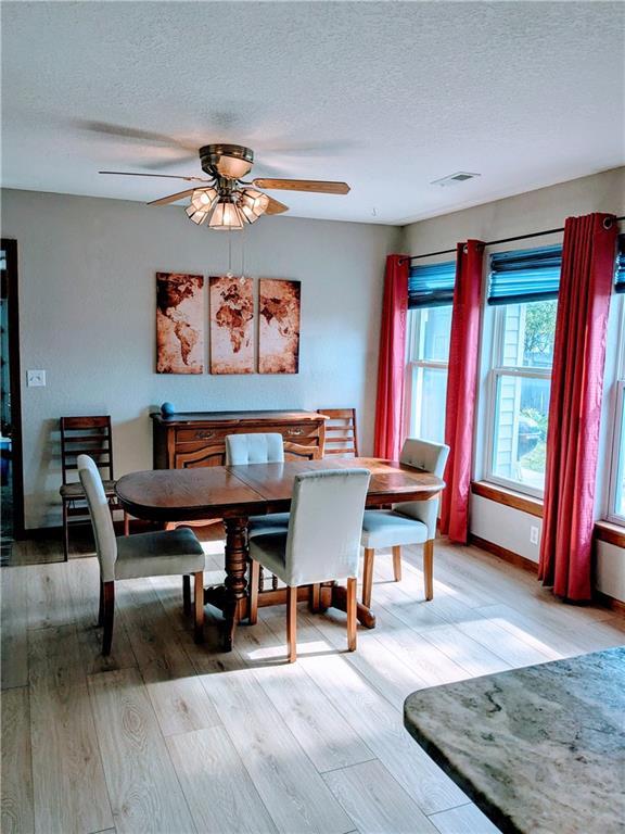 403 S 2nd St, Drexel, MO 64742 - dining area with light wood-type flooring, a ceiling fan, a textured ceiling, and baseboards