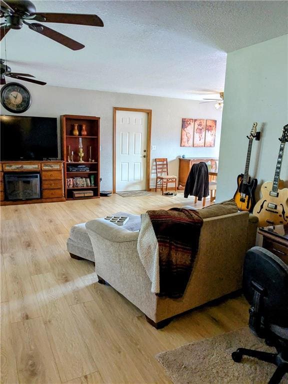 403 S 2nd St, Drexel, MO 64742 - living room featuring ceiling fan, light wood-style flooring, and a textured ceiling