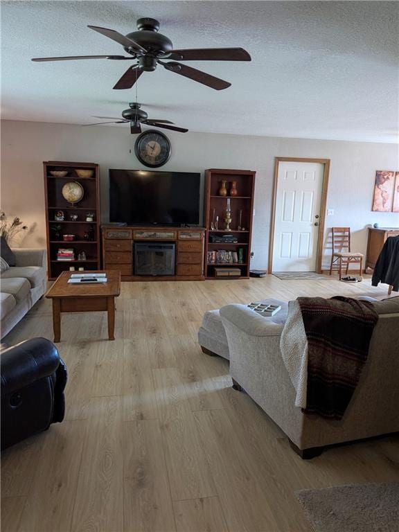 403 S 2nd St, Drexel, MO 64742 - living room with a ceiling fan, light wood-type flooring, a textured ceiling, and a fireplace