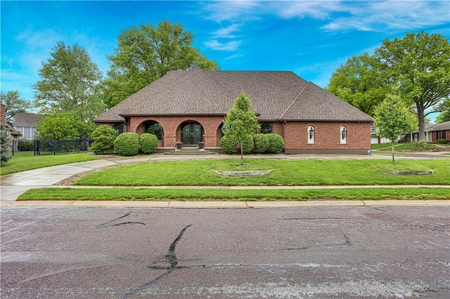 9000 W 104th St, Overland Park, KS 66212 - tudor home with fence, concrete driveway, a front lawn, and brick siding