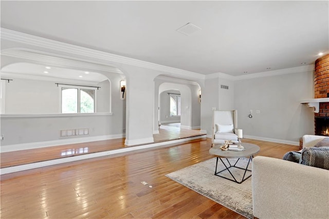 9000 W 104th St, Overland Park, KS 66212 - living area with crown molding, arched walkways, a fireplace, wood finished floors, and baseboards