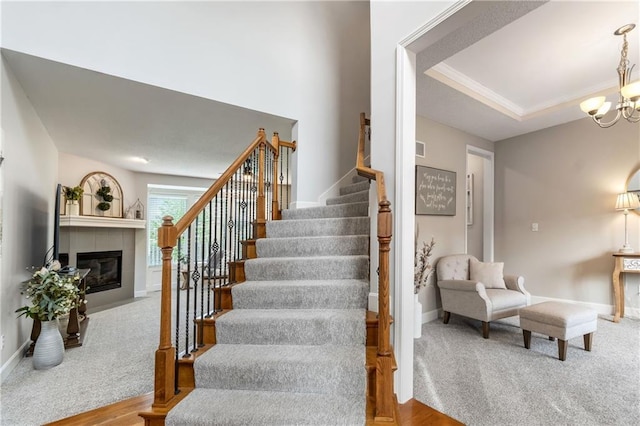 stairs with baseboards, carpet, a notable chandelier, and a tile fireplace