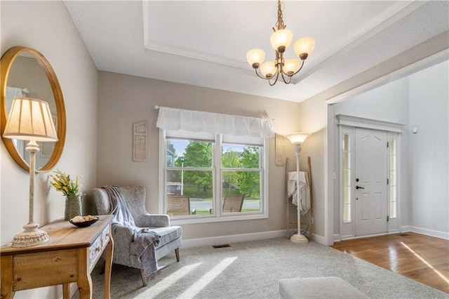 carpeted foyer featuring baseboards, visible vents, and a chandelier