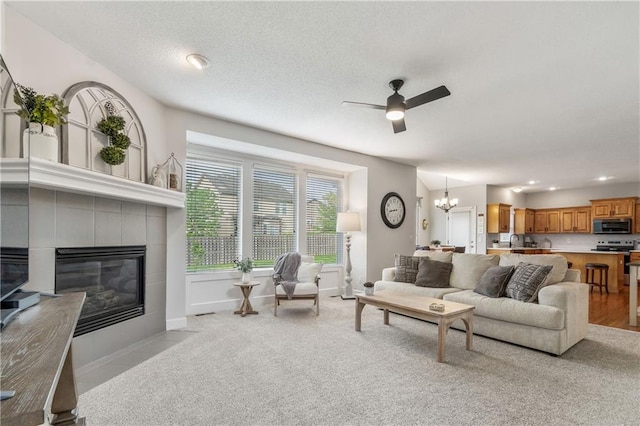living room featuring light carpet, a fireplace, ceiling fan with notable chandelier, recessed lighting, and baseboards