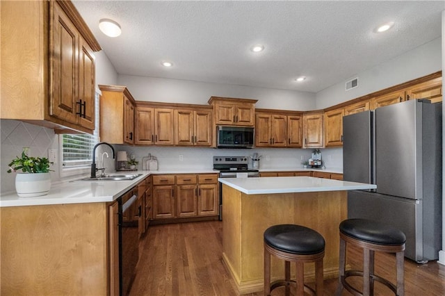 kitchen featuring a sink, brown cabinetry, stainless steel appliances, and dark wood finished floors