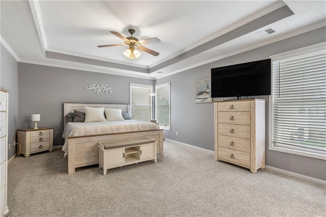 bedroom with a tray ceiling, light colored carpet, ornamental molding, and multiple windows