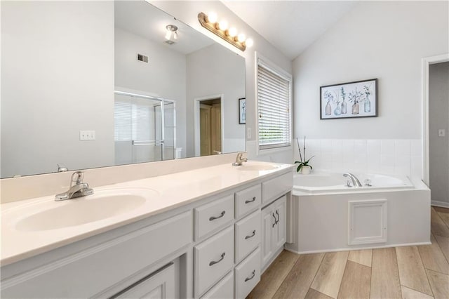 full bathroom with vaulted ceiling, a sink, visible vents, and wood finished floors