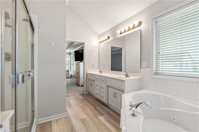 bathroom featuring double vanity, a shower stall, vaulted ceiling, wood finished floors, and a sink