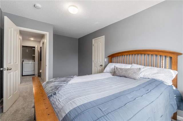 carpeted bedroom with a textured ceiling and washer / dryer