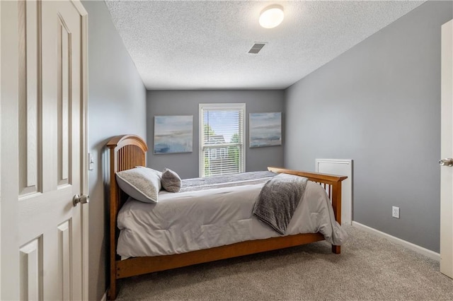 bedroom with carpet floors, a textured ceiling, visible vents, and baseboards