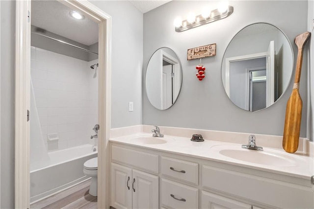 full bath featuring double vanity, toilet, tub / shower combination, and a sink