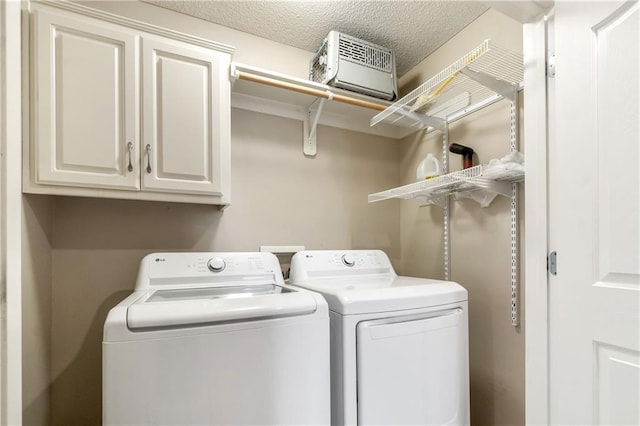 laundry room featuring separate washer and dryer, a textured ceiling, and cabinet space