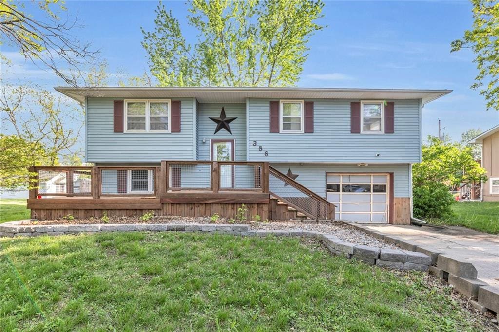 raised ranch with driveway, a wooden deck, a front yard, and a garage