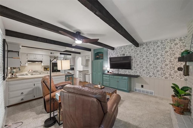 606 W Red Bridge Rd, Kansas City, MO 64114 - living room featuring wallpapered walls, ceiling fan, wainscoting, beamed ceiling, and light carpet