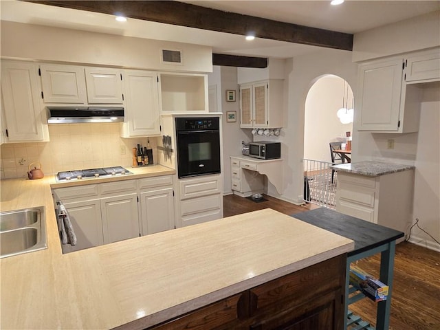 606 W Red Bridge Rd, Kansas City, MO 64114 - kitchen with black oven, arched walkways, under cabinet range hood, light countertops, and backsplash