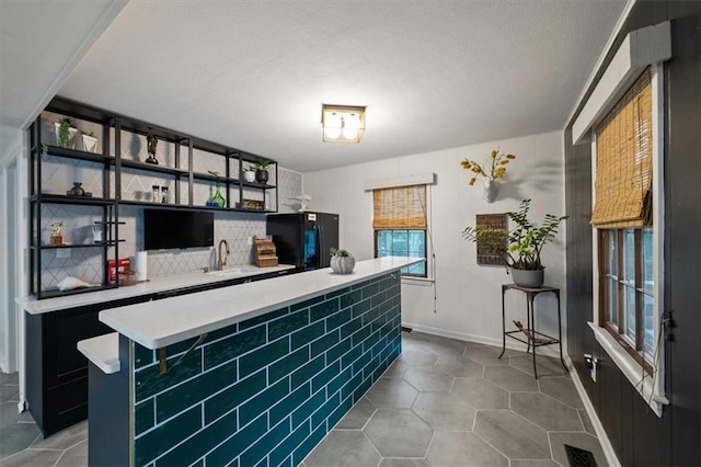 606 W Red Bridge Rd, Kansas City, MO 64114 - kitchen featuring freestanding refrigerator, light countertops, dark cabinetry, a kitchen island, and dark tile patterned flooring