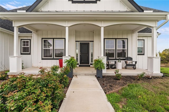 entrance to property with a porch, a shingled roof, and board and batten siding