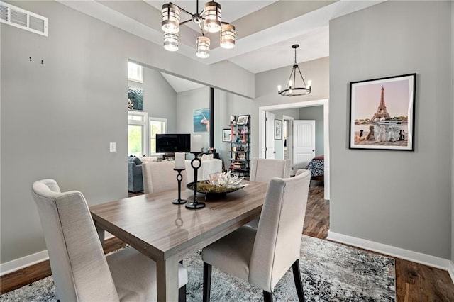 dining space featuring an inviting chandelier, visible vents, baseboards, a high ceiling, and dark wood-type flooring