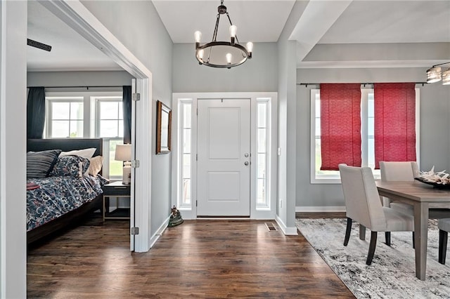 foyer entrance with baseboards, an inviting chandelier, and wood finished floors